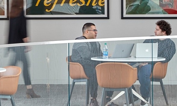 Colleagues sit and talk at Coca-Cola as another passes by