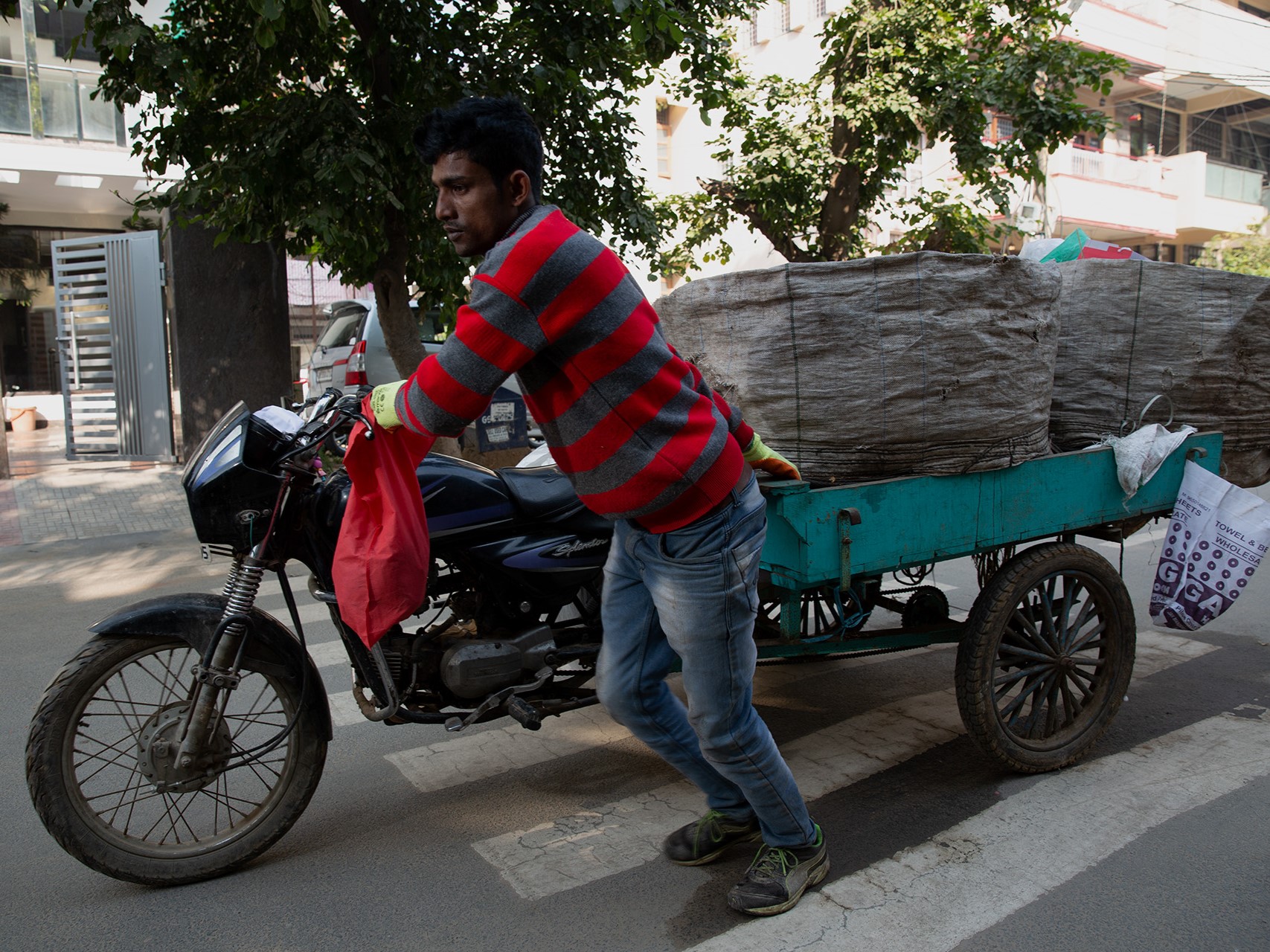 A man walking a motorized trike with containers on the back